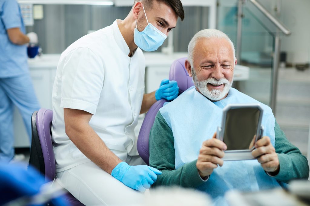 Senior man checking his smile in a hand mirror